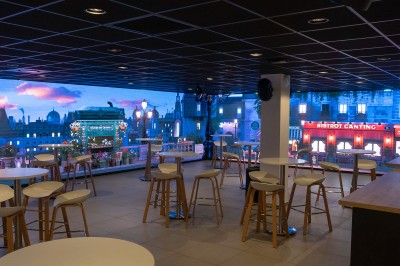 Salle de bain moderne avec lavabo, miroir rond, mur en carrelage noir et blanc, et éclairage tamisé.