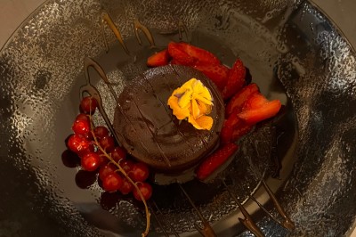 Salle décorée pour les fêtes avec guirlandes lumineuses, table rouge ornée de bougies et mini sapins, scène en arrière-plan.
