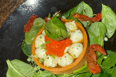 Salle décorée pour les fêtes avec guirlandes lumineuses, table rouge ornée de bougies et mini sapins, scène en arrière-plan.