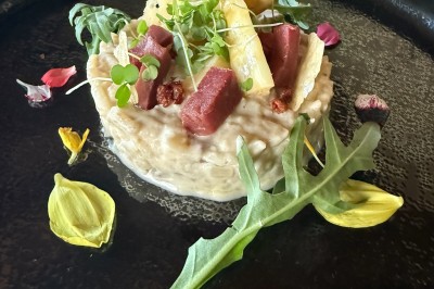 Salle décorée pour les fêtes avec guirlandes lumineuses, table rouge ornée de bougies et mini sapins, scène en arrière-plan.