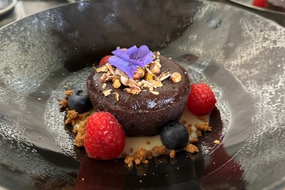 Salle décorée pour les fêtes avec guirlandes lumineuses, table rouge ornée de bougies et mini sapins, scène en arrière-plan.