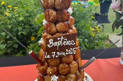 Salle décorée pour les fêtes avec guirlandes lumineuses, table rouge ornée de bougies et mini sapins, scène en arrière-plan.