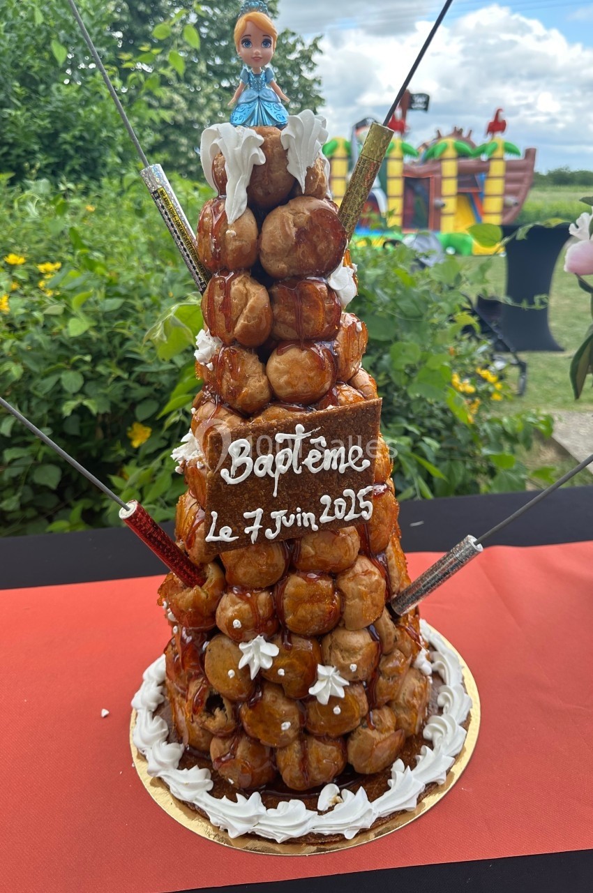 Pièce montée de choux décorée pour un baptême, avec une inscription ’Baptême le 7 juin 2015’ et une figurine au sommet.