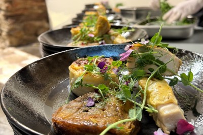 Salle décorée pour les fêtes avec guirlandes lumineuses, table rouge ornée de bougies et mini sapins, scène en arrière-plan.