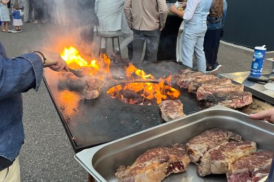 Salle décorée pour les fêtes avec guirlandes lumineuses, table rouge ornée de bougies et mini sapins, scène en arrière-plan.