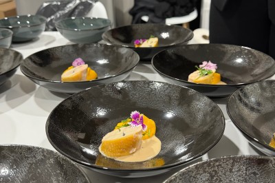 Salle décorée pour les fêtes avec guirlandes lumineuses, table rouge ornée de bougies et mini sapins, scène en arrière-plan.