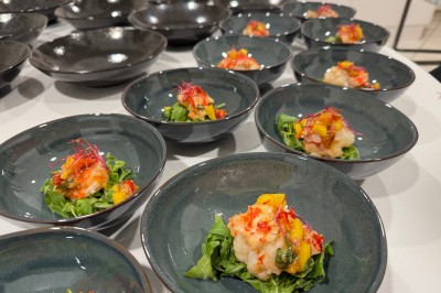 Salle décorée pour les fêtes avec guirlandes lumineuses, table rouge ornée de bougies et mini sapins, scène en arrière-plan.