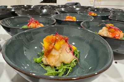 Salle décorée pour les fêtes avec guirlandes lumineuses, table rouge ornée de bougies et mini sapins, scène en arrière-plan.