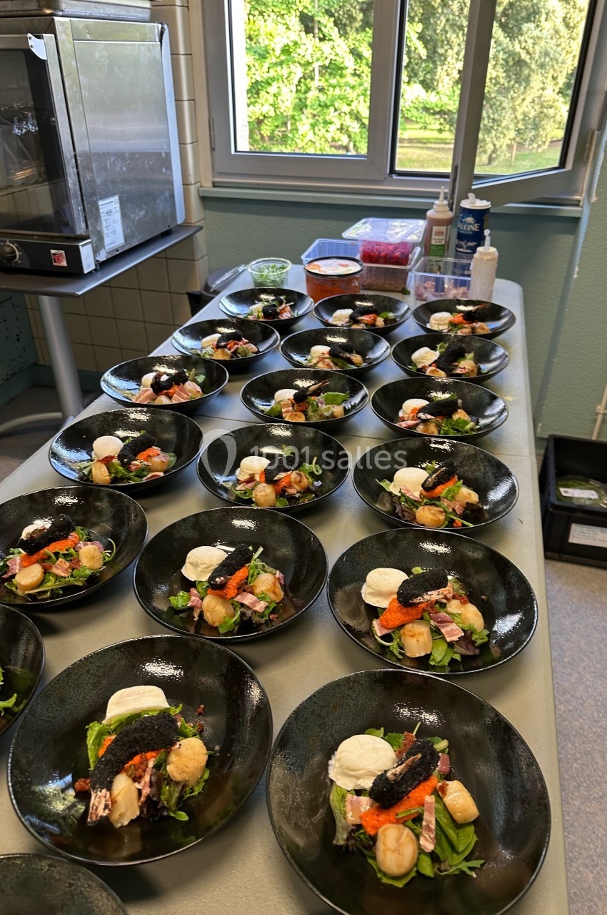 Assiettes dressées avec des entrées composées de légumes, noix de Saint-Jacques et garnitures, alignées sur une table.