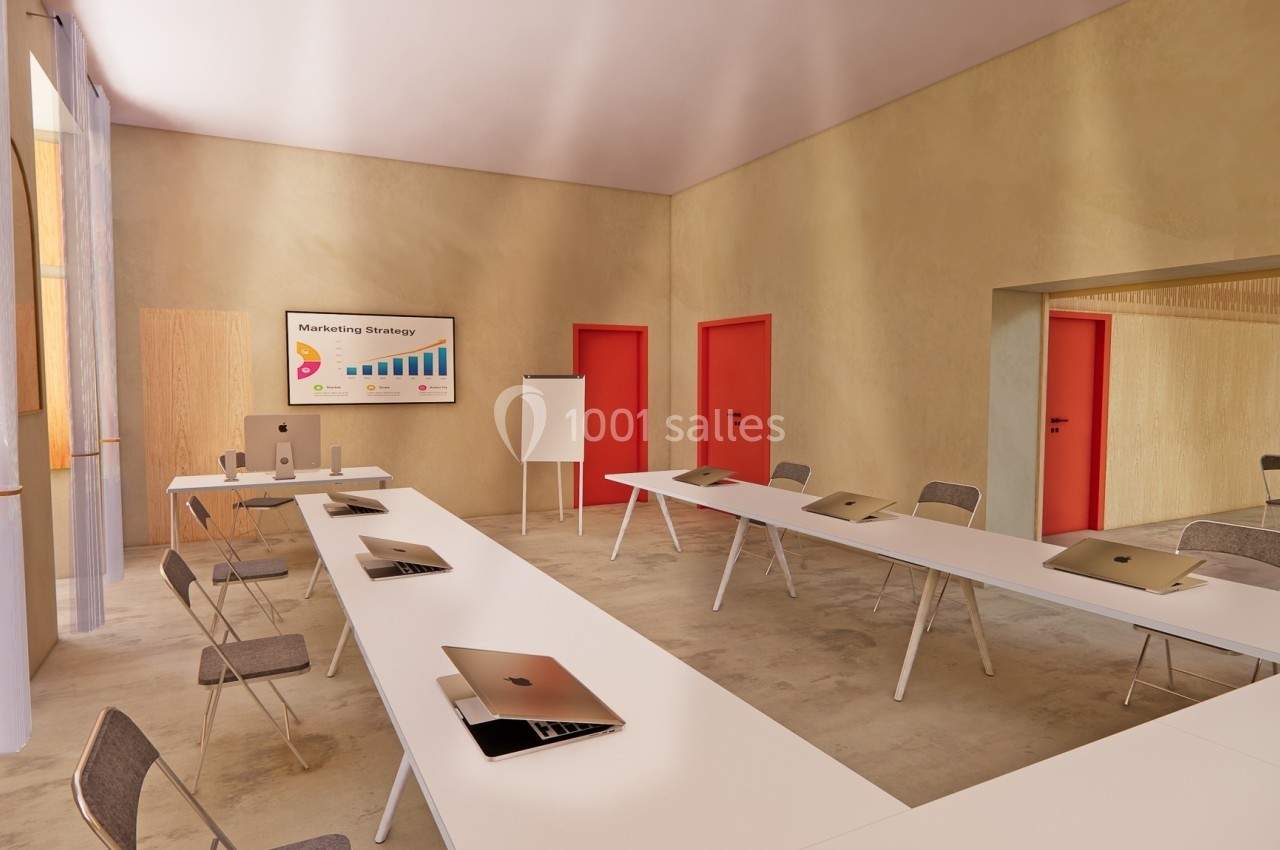 Salle de réunion lumineuse avec tables en U, chaises, ordinateurs portables et écran affichant une présentation.