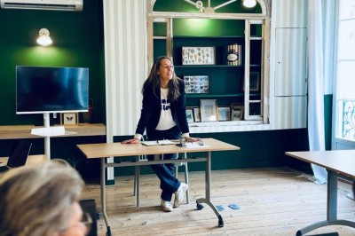 Fauteuil bleu et table basse dans un salon au style vintage avec papier peint fleuri et armoire en bois.