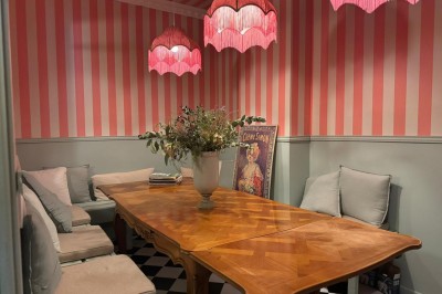 Fauteuil bleu et table basse dans un salon au style vintage avec papier peint fleuri et armoire en bois.