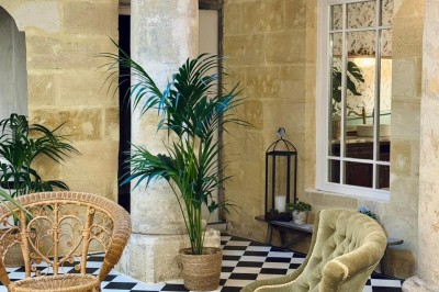 Fauteuil bleu et table basse dans un salon au style vintage avec papier peint fleuri et armoire en bois.