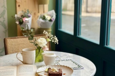 Fauteuil bleu et table basse dans un salon au style vintage avec papier peint fleuri et armoire en bois.