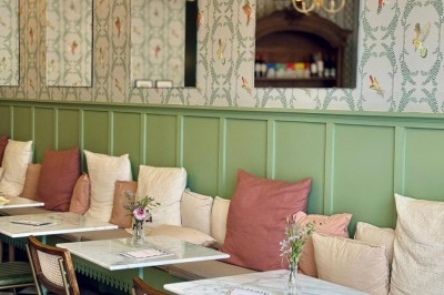Fauteuil bleu et table basse dans un salon au style vintage avec papier peint fleuri et armoire en bois.