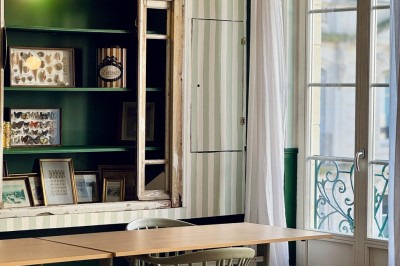 Fauteuil bleu et table basse dans un salon au style vintage avec papier peint fleuri et armoire en bois.