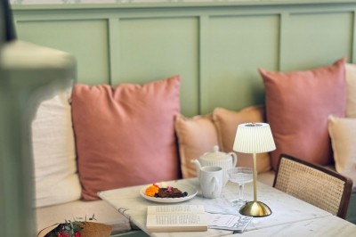 Fauteuil bleu et table basse dans un salon au style vintage avec papier peint fleuri et armoire en bois.