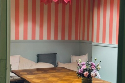 Fauteuil bleu et table basse dans un salon au style vintage avec papier peint fleuri et armoire en bois.