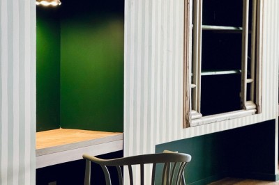 Fauteuil bleu et table basse dans un salon au style vintage avec papier peint fleuri et armoire en bois.