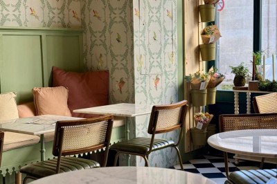 Fauteuil bleu et table basse dans un salon au style vintage avec papier peint fleuri et armoire en bois.