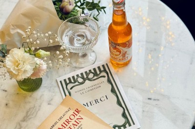 Fauteuil bleu et table basse dans un salon au style vintage avec papier peint fleuri et armoire en bois.