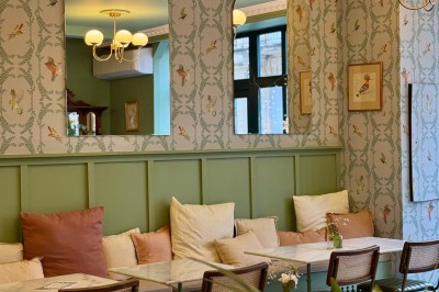 Fauteuil bleu et table basse dans un salon au style vintage avec papier peint fleuri et armoire en bois.