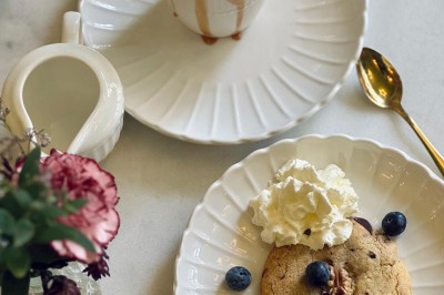 Fauteuil bleu et table basse dans un salon au style vintage avec papier peint fleuri et armoire en bois.