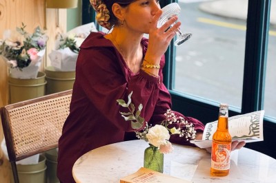 Fauteuil bleu et table basse dans un salon au style vintage avec papier peint fleuri et armoire en bois.