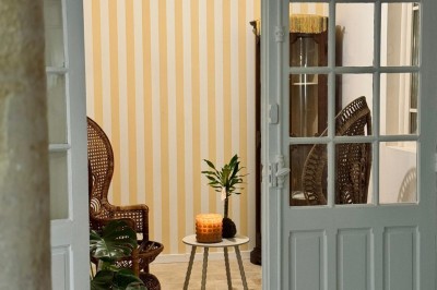 Fauteuil bleu et table basse dans un salon au style vintage avec papier peint fleuri et armoire en bois.