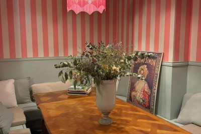 Fauteuil bleu et table basse dans un salon au style vintage avec papier peint fleuri et armoire en bois.