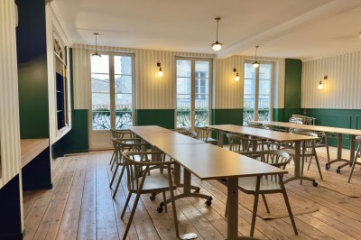Fauteuil bleu et table basse dans un salon au style vintage avec papier peint fleuri et armoire en bois.