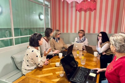 Fauteuil bleu et table basse dans un salon au style vintage avec papier peint fleuri et armoire en bois.