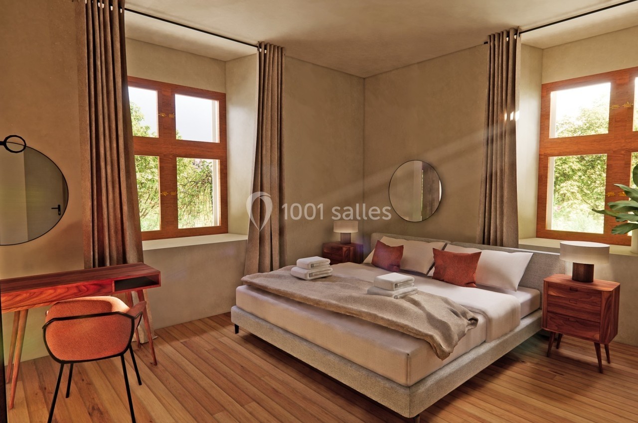 Chambre lumineuse avec lit double, draps pliés, mobilier en bois, miroirs ronds et grandes fenêtres donnant sur la verdure.