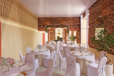 Vue aérienne d'un château en briques rouges entouré d'une pelouse bien entretenue et d'arbres.