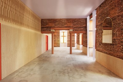 Vue aérienne d'un château en briques rouges entouré d'une pelouse bien entretenue et d'arbres.
