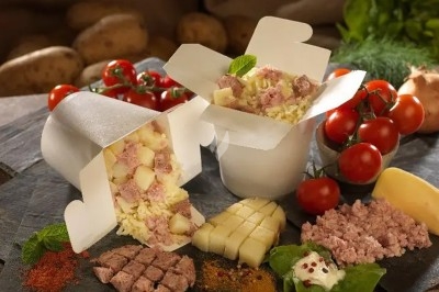 Repas à emporter composé de pommes de terre, fromage et viande hachée, entouré d'ingrédients frais.