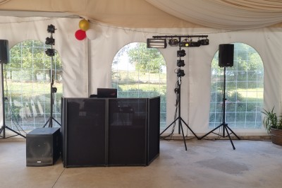 Tables et chaises installées en extérieur près d'une piscine, avec des stands et des arbres en arrière-plan.