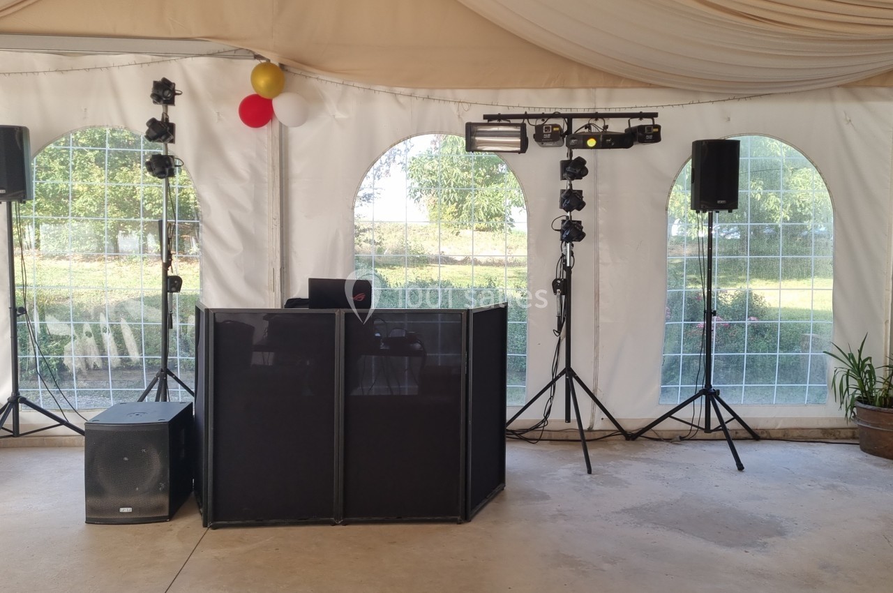 Installation de matériel de sonorisation et d'éclairage dans une tente avec vue sur un jardin à travers des fenêtres.