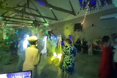 Des personnes dansent dans une salle décorée avec des guirlandes lumineuses et des jeux de lumière colorés.