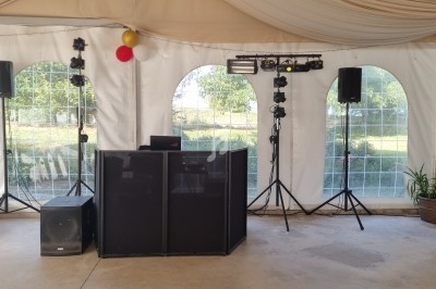 Installation de matériel de sonorisation et d'éclairage dans une tente avec vue sur un jardin à travers des fenêtres.