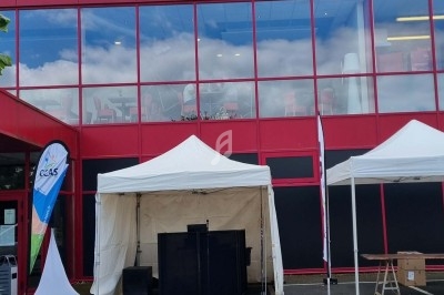 Façade d'un bâtiment rouge avec l'enseigne ’Skybowl’, devant laquelle sont installées des tentes blanches.