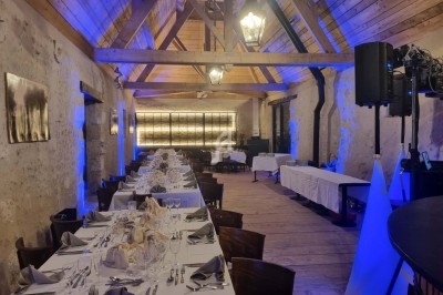 Tables et chaises disposées en extérieur sur une pelouse, avec des stands, des tentes et des camions en arrière-plan.