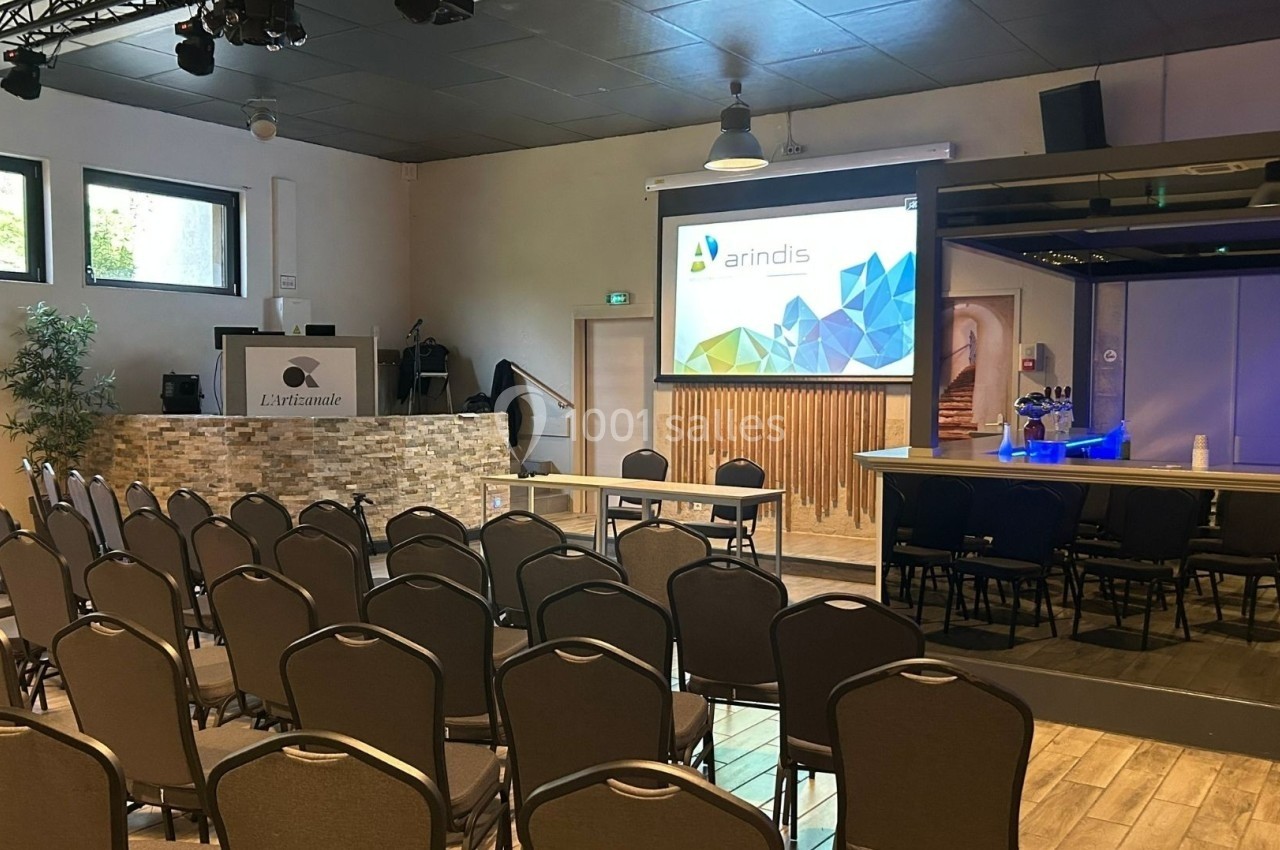 Salle de conférence équipée de chaises, d'un écran de projection, d'un pupitre et d'un bar en arrière-plan.