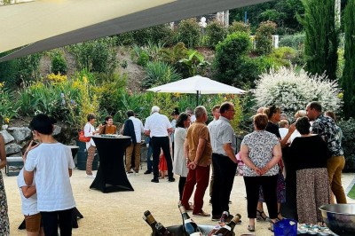 Des invités se servent des amuse-bouches sur des plateaux tenus par une serveuse lors d'un événement convivial.