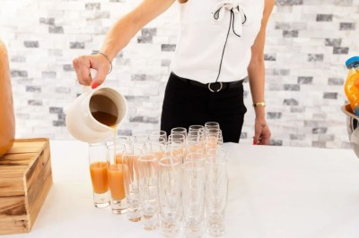 Des invités se servent des amuse-bouches sur des plateaux tenus par une serveuse lors d'un événement convivial.