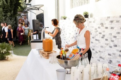 Des invités se servent des amuse-bouches sur des plateaux tenus par une serveuse lors d'un événement convivial.