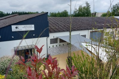 Miniature Location salle Pont-Évêque (Isère) - L'Artizanale #40 Bâtiment avec toit en tuiles, façade blanche, enseigne visible et espace extérieur aménagé avec végétation.