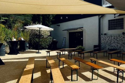 Miniature Location salle Pont-Évêque (Isère) - L'Artizanale #21 Bâtiment avec toit en tuiles, façade blanche, enseigne visible et espace extérieur aménagé avec végétation.