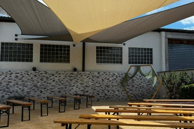 Miniature Location salle Pont-Évêque (Isère) - L'Artizanale #25 Bâtiment avec toit en tuiles, façade blanche, enseigne visible et espace extérieur aménagé avec végétation.