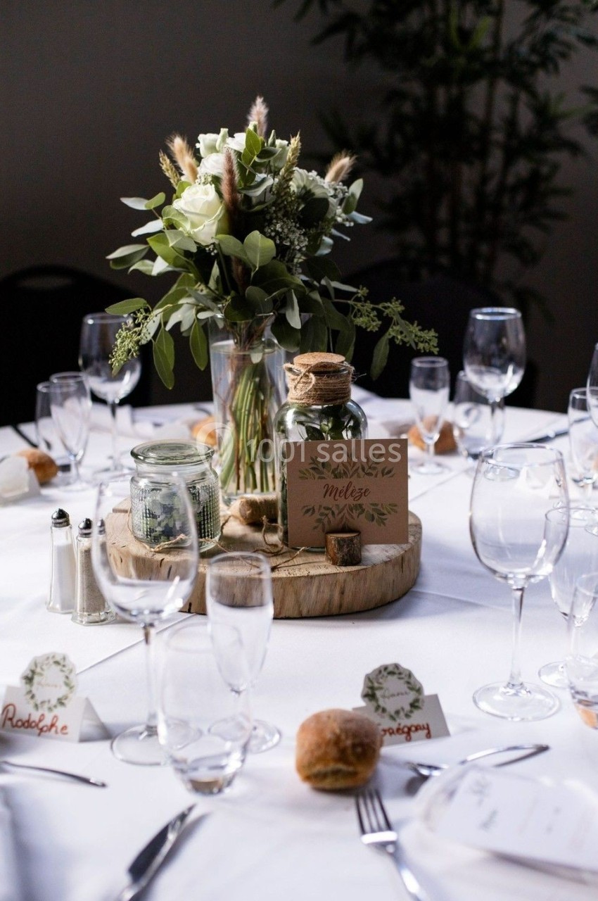 Table décorée pour un mariage avec centre de table floral, bougies, menus personnalisés et vaisselle élégante.